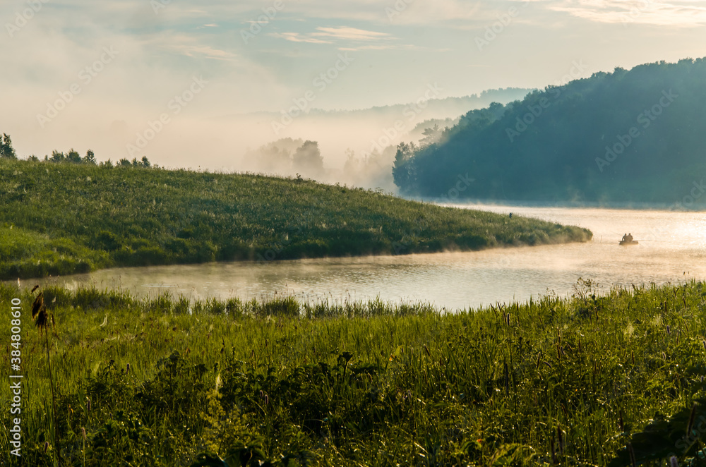 Obraz premium thick morning fog in the summer forest near the reservoir. fishermen on a boat