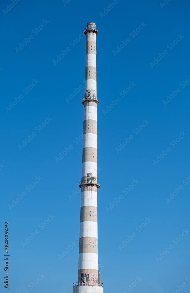 Old industrial plant chimney, sunny day, vertical photo.