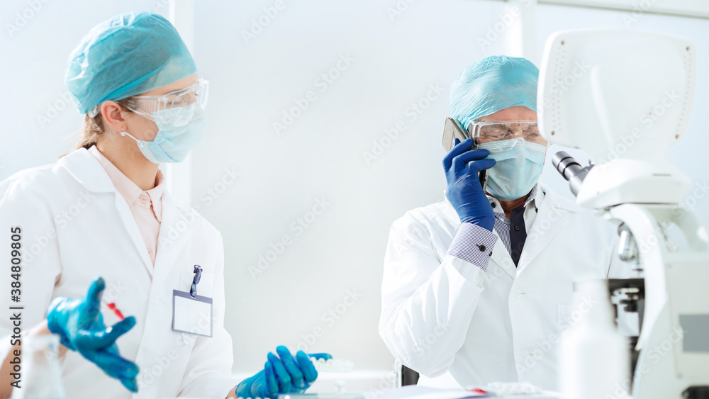 scientists in a protective mask talking on a mobile phone. scientists in a protective mask talking on a mobile phone.