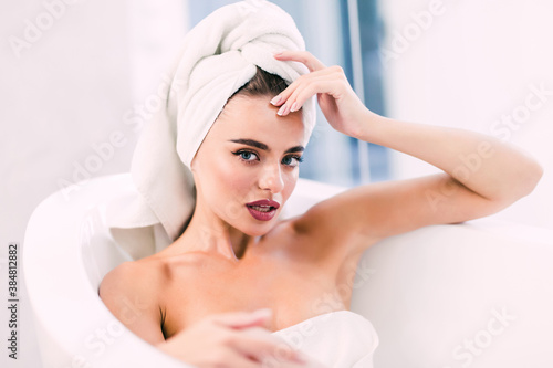 Young woman taking a bath with a towel on her head. Beauty concepts