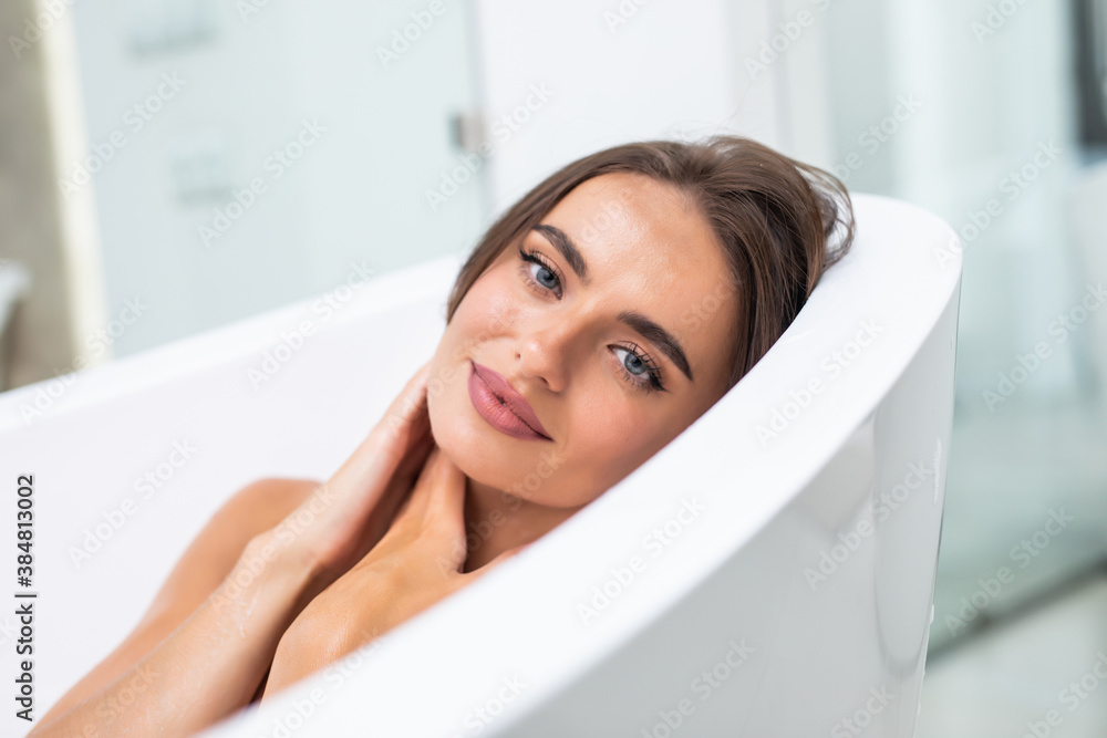 Young pretty woman lying in bathtub in bathroom. Female relaxing in bathtub Young pretty woman lying in bathtub in bathroom. Female relaxing in bathtub