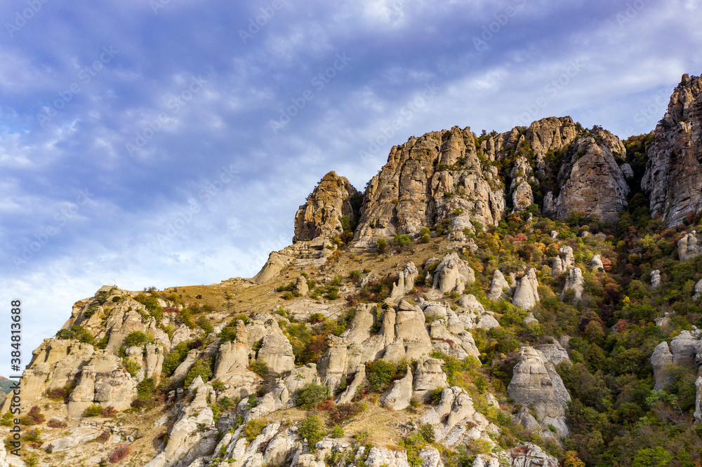 Fototapeta premium a panoramic view of the beautiful mountains with unusual ledges and rocks against the background of the sky and the valley filmed from a drone