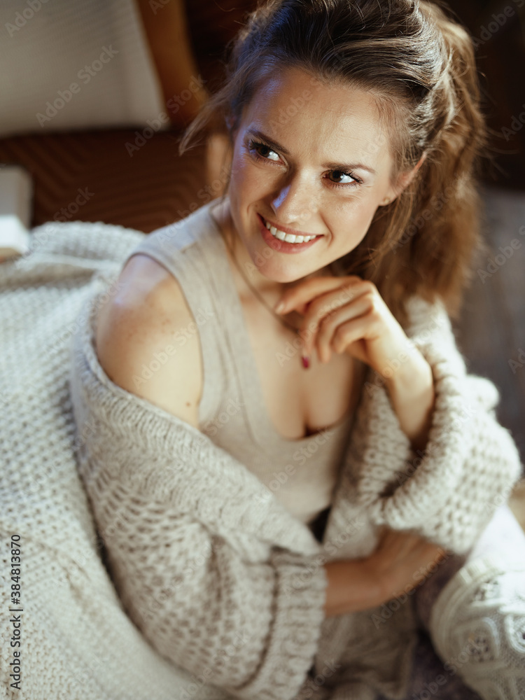 happy young woman sitting near sofa in modern living room happy young woman sitting near sofa in modern living room