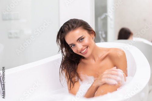 Portrait of young woman sitting in bathtub at home