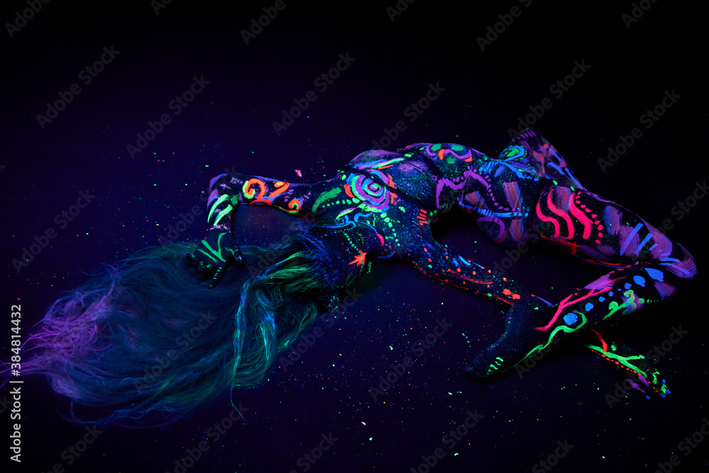 Obraz premium Art woman body art on the body dancing in ultraviolet light. Bright abstract drawings on the woman body neon color. Colored hair and face