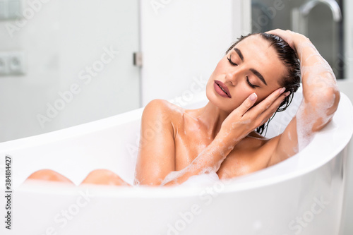 Joyful girl lying in foam while taking a bath at home