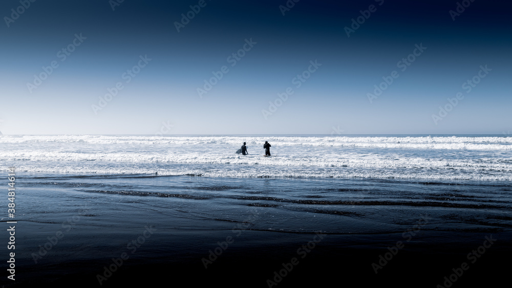 Silhouette of 2 Surfers Standing in the Ocean