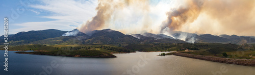Obraz na płótnie Panoramic view of a wildfire burning through the dry forests and threatening houses and buildings in the mountains w salonie