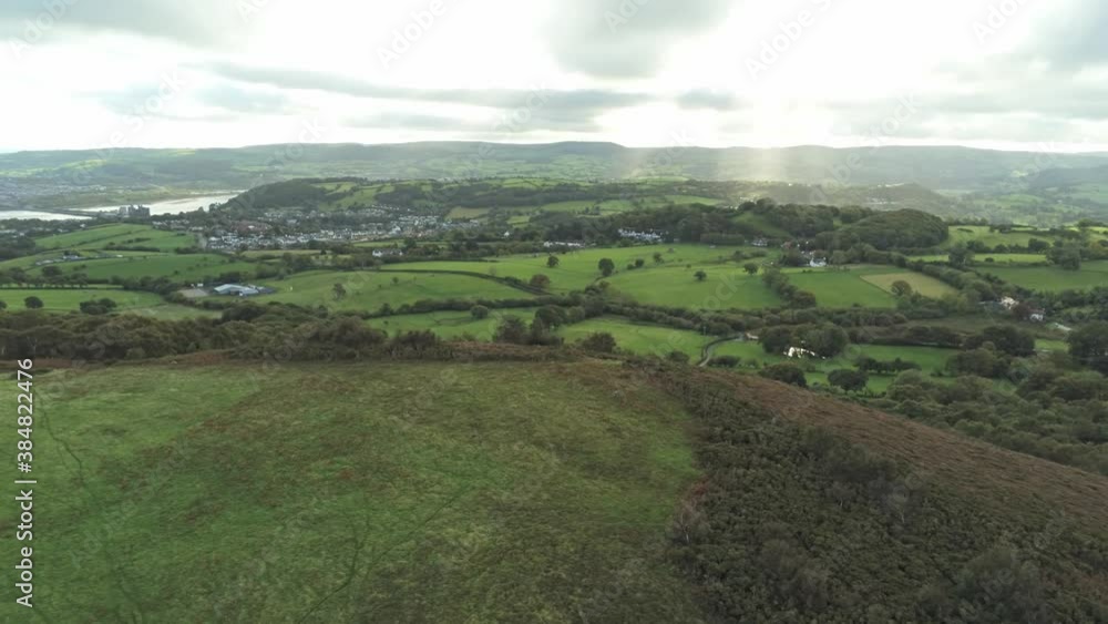 Sunbeams moving across overcast British agricultural rural village countryside morning aerial view left pan Sunbeams moving across overcast British agricultural rural village countryside morning aerial view left pan