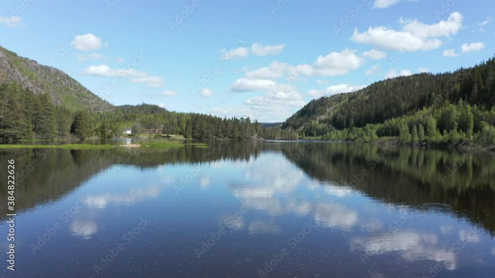 Aerial view between trees, over a calm, reflecting Tovdalelva river, on a sunny day, in Agder,, Norway - dolly, drone shot Aerial view between trees, over a calm, reflecting Tovdalelva river, on a sunny day, in Agder,, Norway - dolly, drone shot
