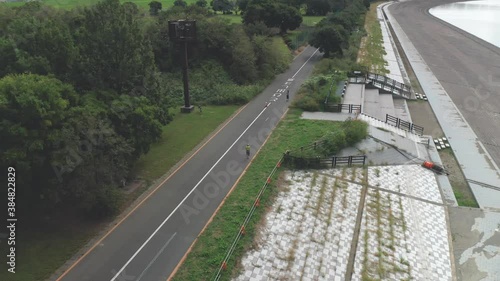 Japanese Woman Jogging Along The Arakawa River At Early Morning In Saitama, Japan. - aerial drone shot photo