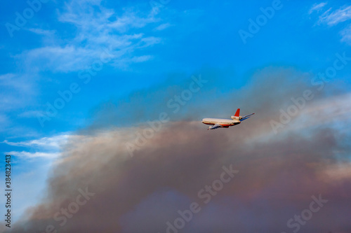 Fire plane flying through dense dark wildfire smoke to drop retardant