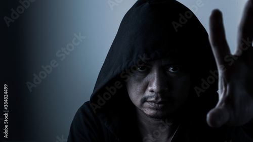 Asiain man wearing black cloak in the dark.