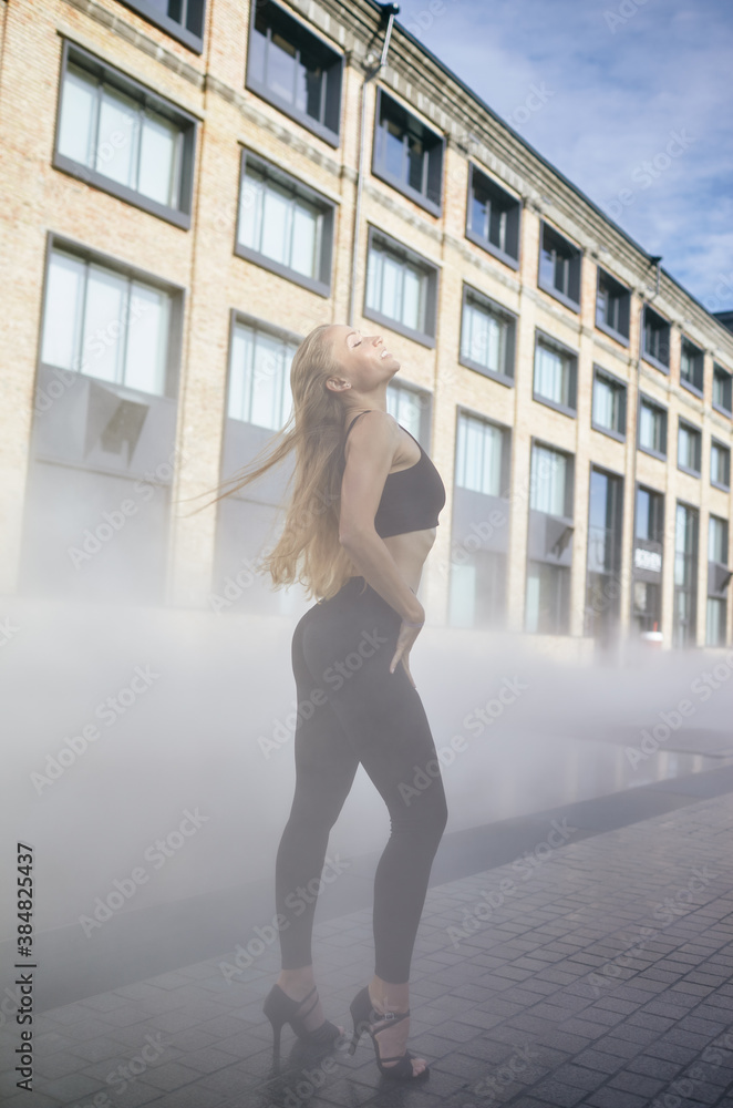 Beautiful woman dancer with long blond hair posing on city street. Female dancing improvisation - latina dance, tango, contemporary and bachata