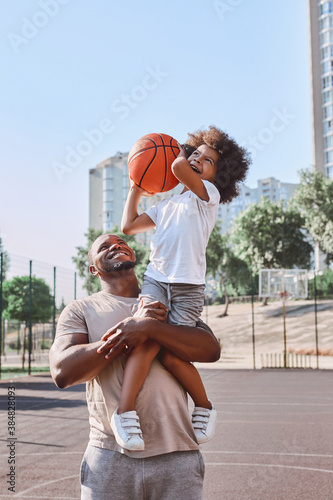 Happy dad holding kid on his shoulder during basketball