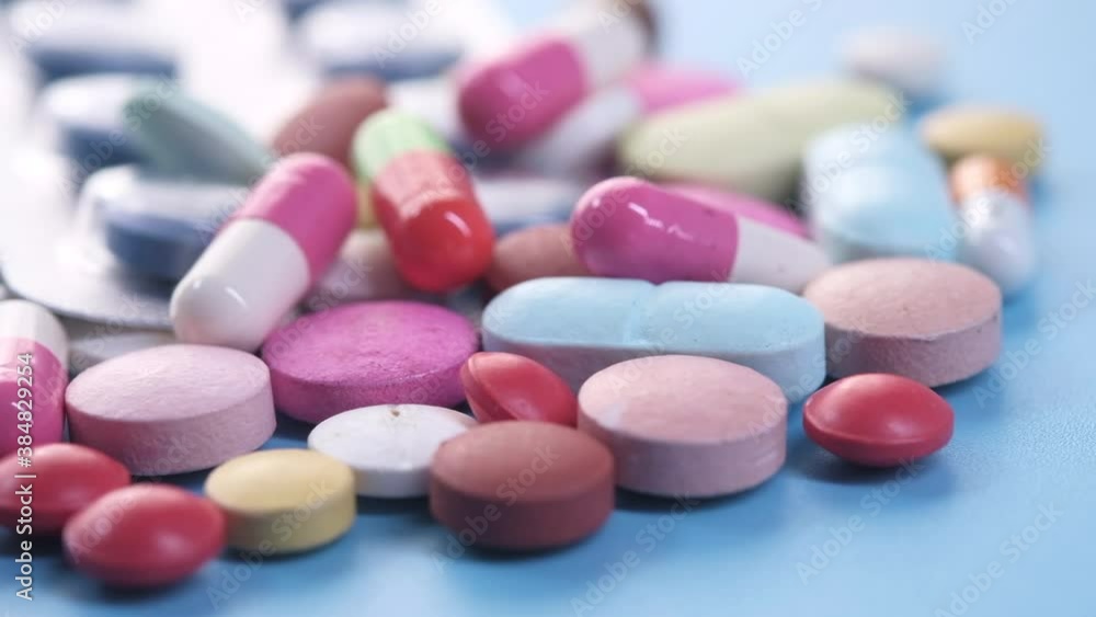 close up of colorful pills spilling on blue background 