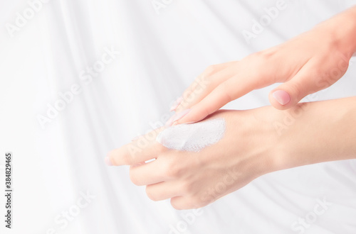 The concept of cosmetics and care for face and body. Women s hands with cream on a white background. Copy space