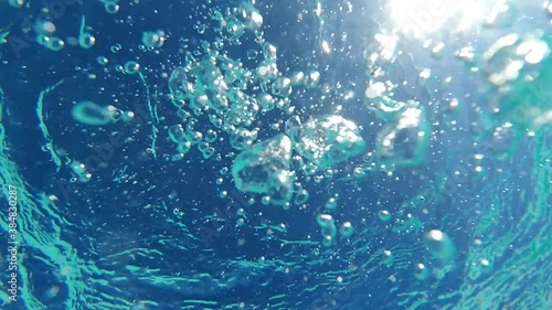 Underwater slow motion bubbles moving to surface in turquoise crystal clear pool photo