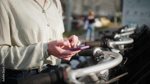 Woman takes bike bicycle in sharing parking lot, phone application for rent bike.