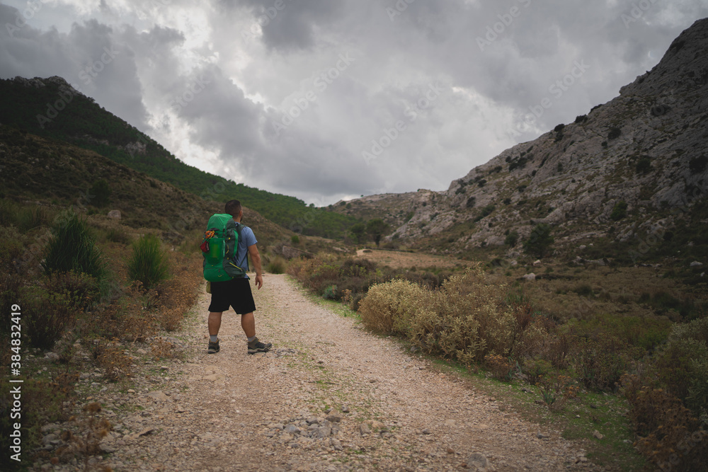 A hiker stays looking the stunning views of Serra de Tramuntana
