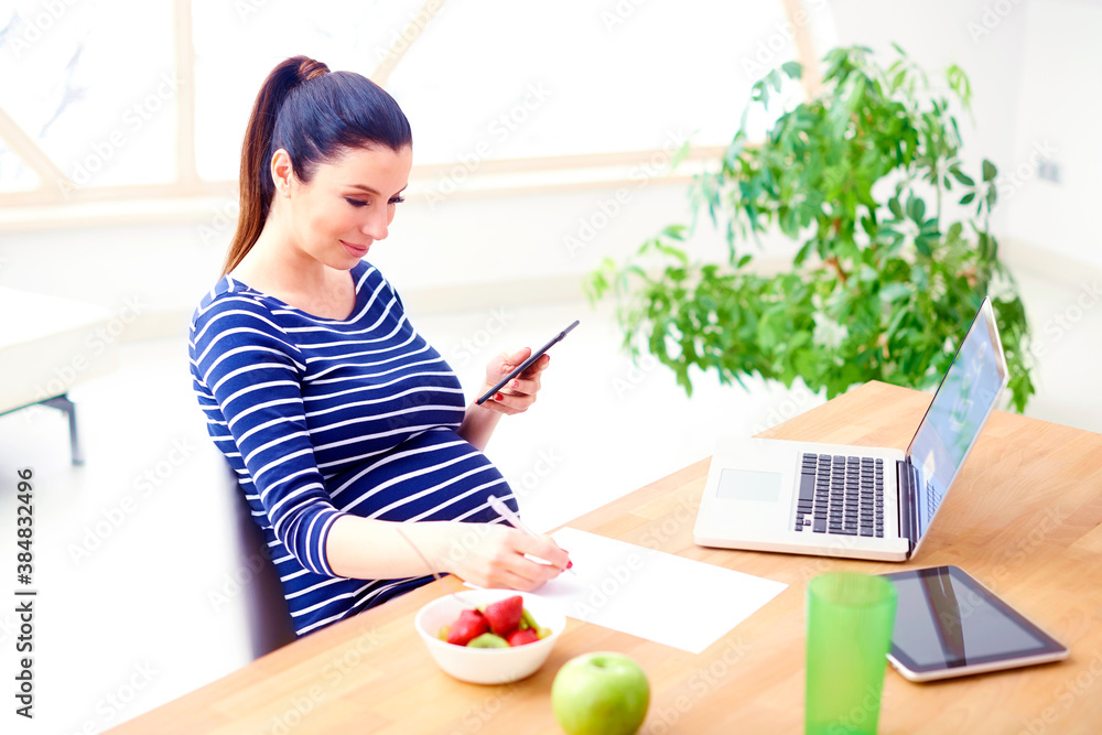 Pregnant woman using mobile phone and laptop Pregnant woman using mobile phone and laptop