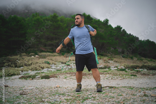 A man is putting on his green bag during a hike in Serra de Tramuntana