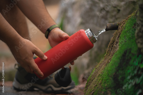 Detail of hands filling up an aluminum bottle from a natural source