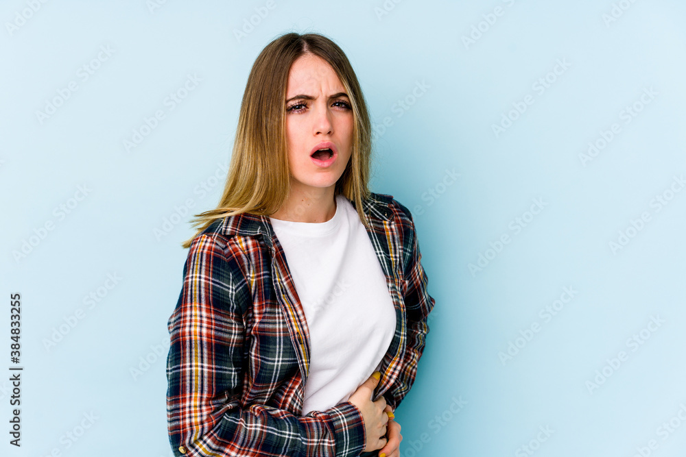 Young caucasian woman isolated on blue background having a liver pain, stomach ache. Young caucasian woman isolated on blue background having a liver pain, stomach ache.
