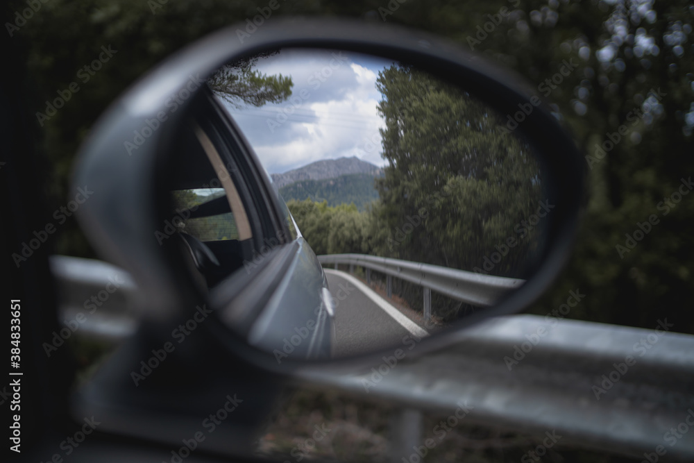 Detail of the rear mirror of a car driving through a mountain road