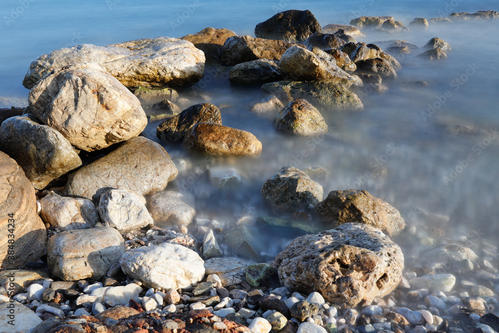 Obraz premium Rocky stretch of coast of the Mediterranean Sea on the Greek Aegean island of Samos with a calm water surface.