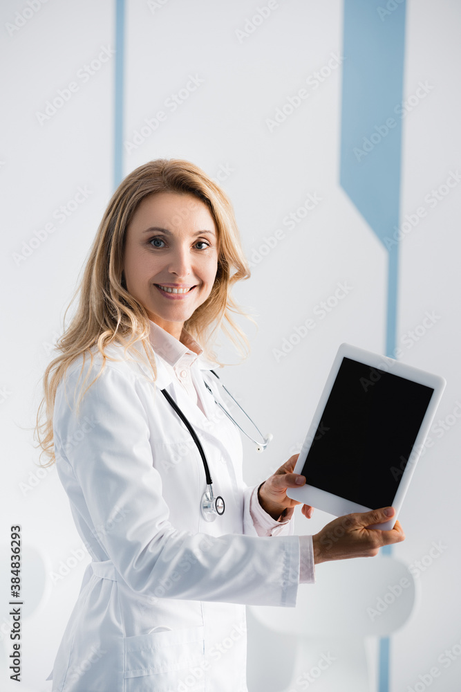 Blonde doctor showing digital tablet with blank screen in clinic Blonde doctor showing digital tablet with blank screen in clinic