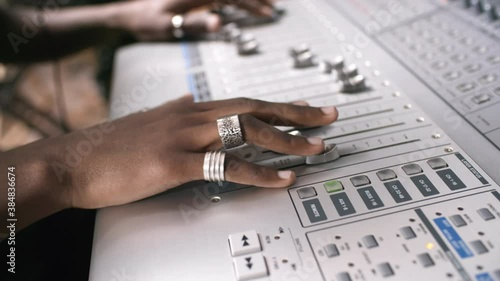Handheld tracking with close up of hands of black male audio engineer using mixing desk in recording studio