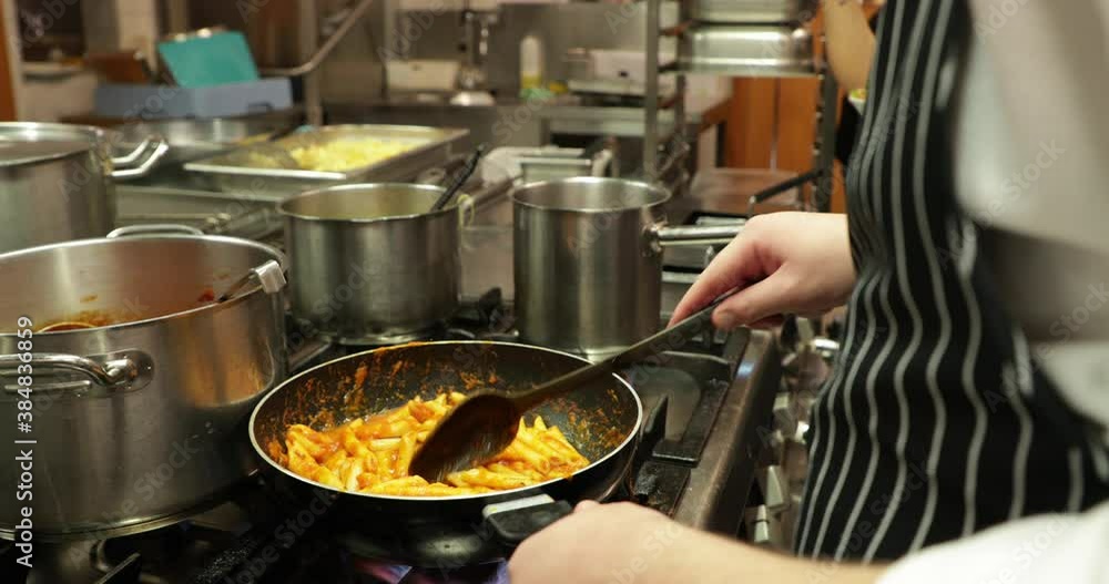Stirring Penne Pasta With Sauce In A Skillet At The Restaurant Kitchen - close up, slow motion Stirring Penne Pasta With Sauce In A Skillet At The Restaurant Kitchen - close up, slow motion