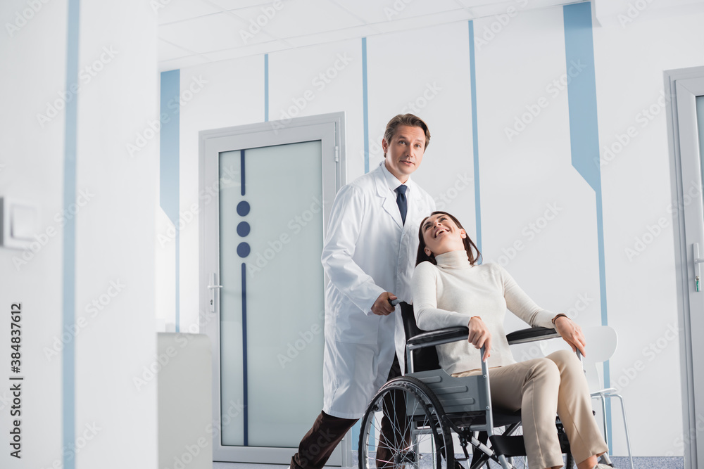 Selective focus of excited patient in wheelchair looking at doctor in clinic Selective focus of excited patient in wheelchair looking at doctor in clinic