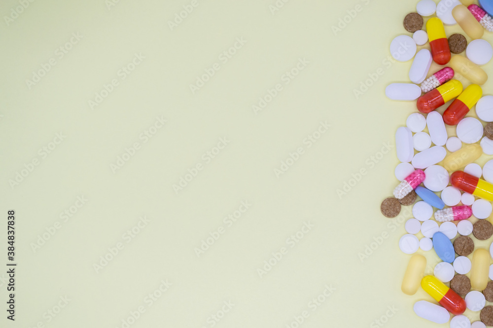 Obraz premium A lot of colorful tablets and pills on the right. Yellow background, copy space