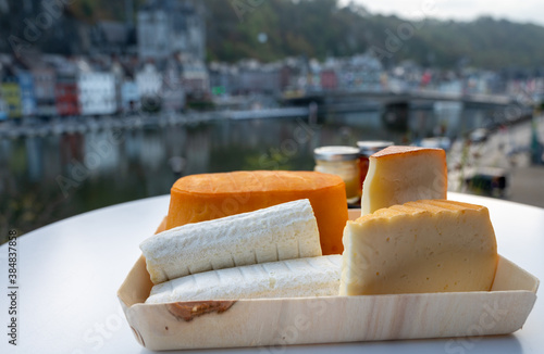 Cheese collection, Belgian abbey cheeses made with brown trappist beer and fine herbs and view on Maas river in Dinant, Wallonia, Belgium photo