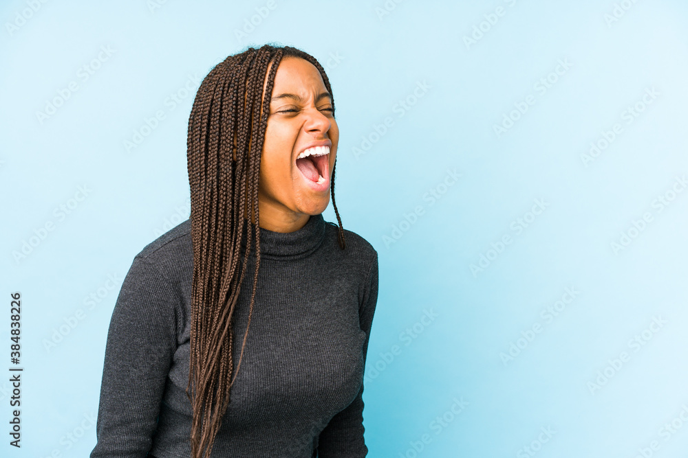 Young african american woman isolated on blue background shouting towards a copy space Young african american woman isolated on blue background shouting towards a copy space