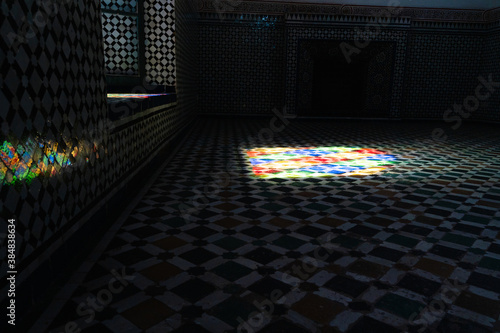 Dark room decorated with tiles and mosaic while light enters from a window
