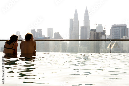 Photography Two people reclining in a pool in a building overlooking the city of Kuala Lumpu