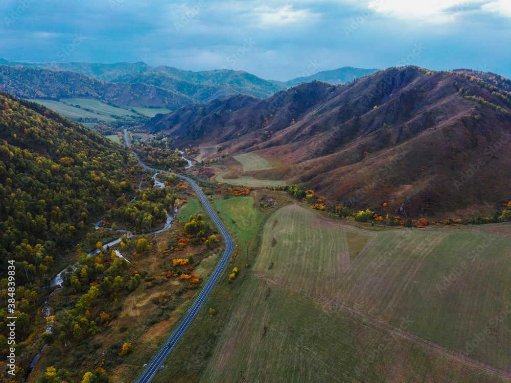 Aerial panoramic view of autumn mountain landscape at sunset. Drone shooting of scenic autumn backgrounds