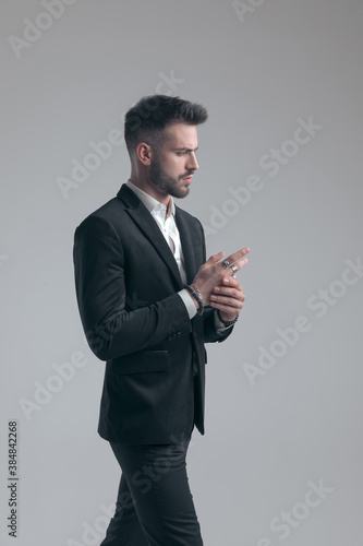 Confident elegant man adjusting his rings, wearing suit