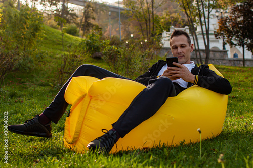 Feel Free. Handsome Young Man Lying On Inflatable Sofa Lamzac While Resting in park. photo