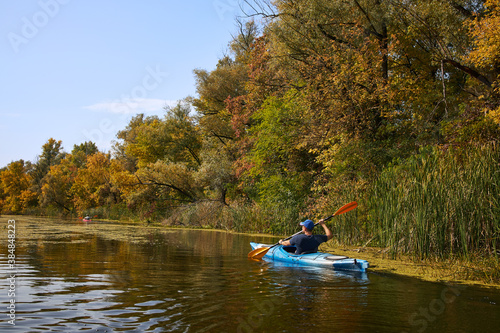 Man kayaking on lake in autumn. Active tourism. © kobeza