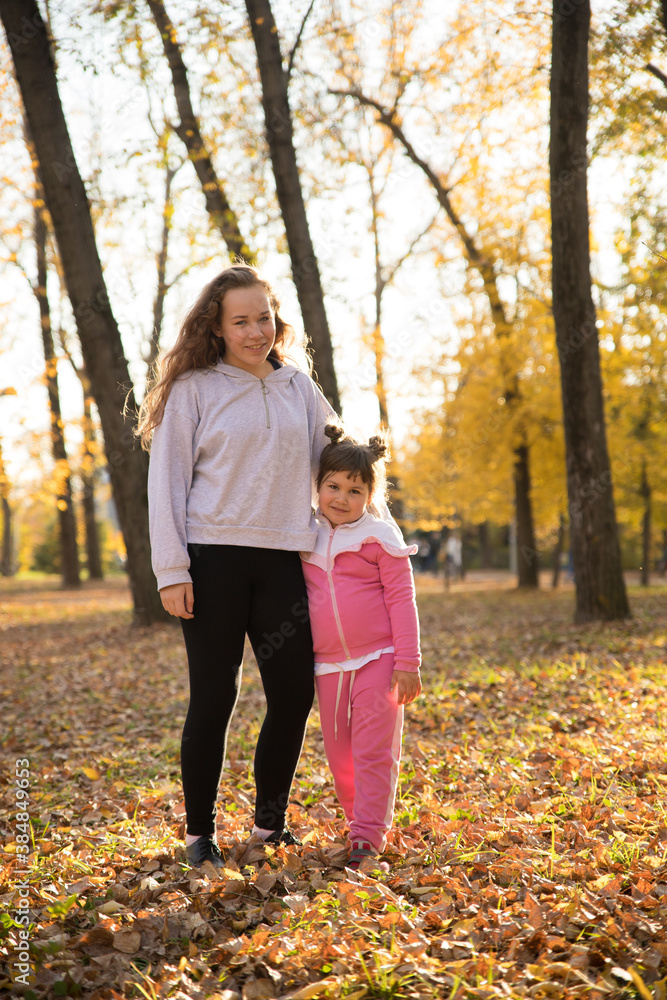 Two sisters standing in autumn park hugging Two sisters standing in autumn park hugging