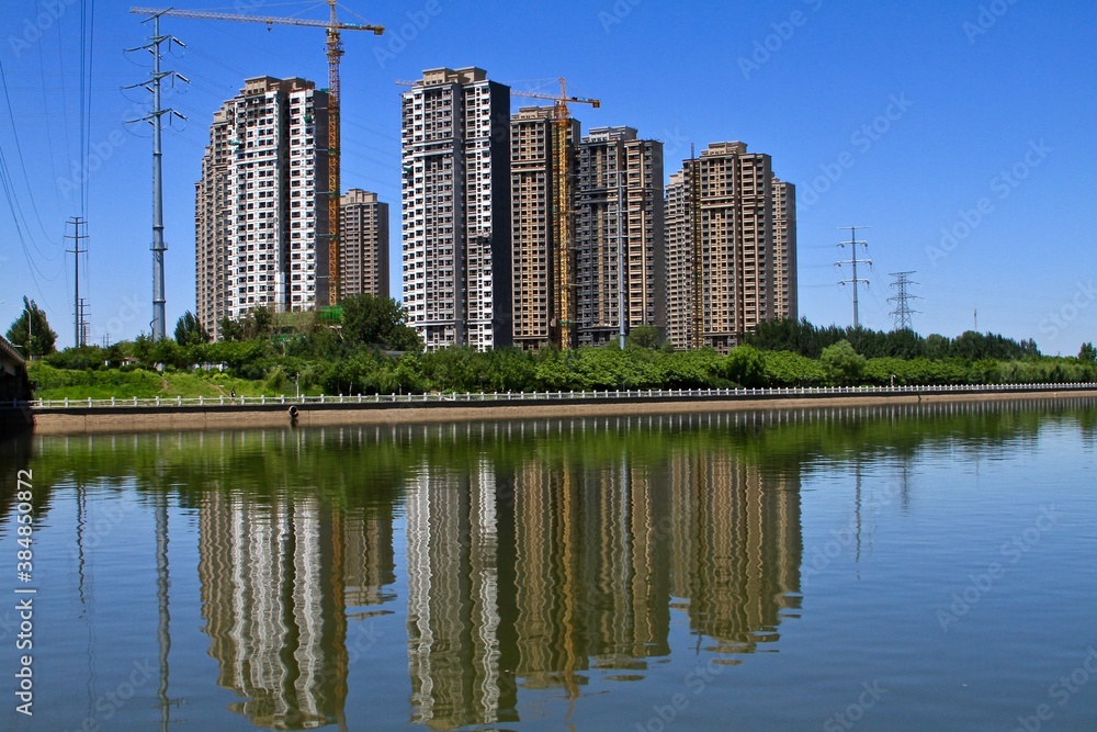Modern apartment building under construction with a pond in the front