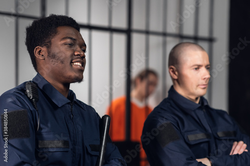 Valokuva Prison guards smile as they stand with batons near cells with dangerous criminals