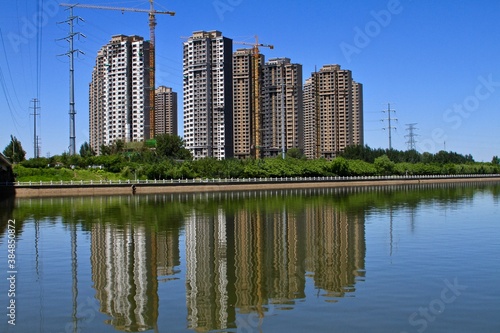 Modern apartment building under construction with a pond in the front