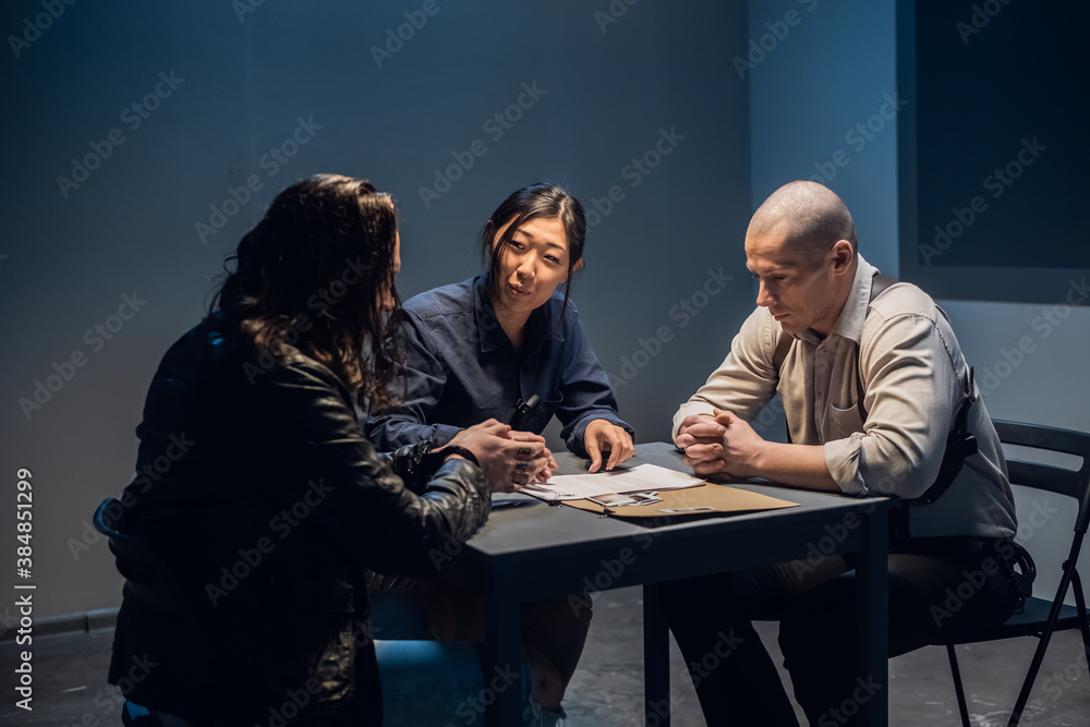 Fototapeta premium In the police station's interrogation room, good and bad cops are questioning a theft suspect in a leather jacket