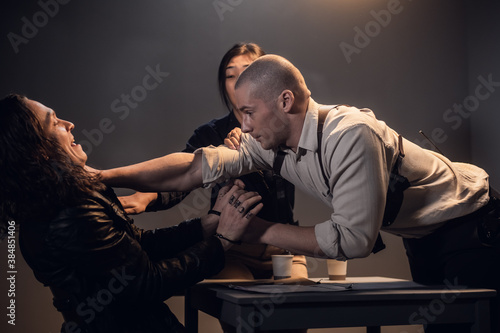 Valokuva A bad cop threatens a suspect with a gun at a police station in the presence of