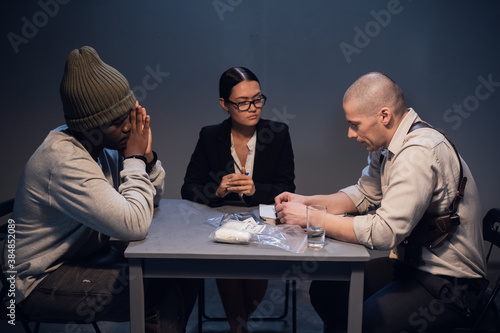 A black drug addict is interrogated at a police station by an experienced investigator and government lawyer.